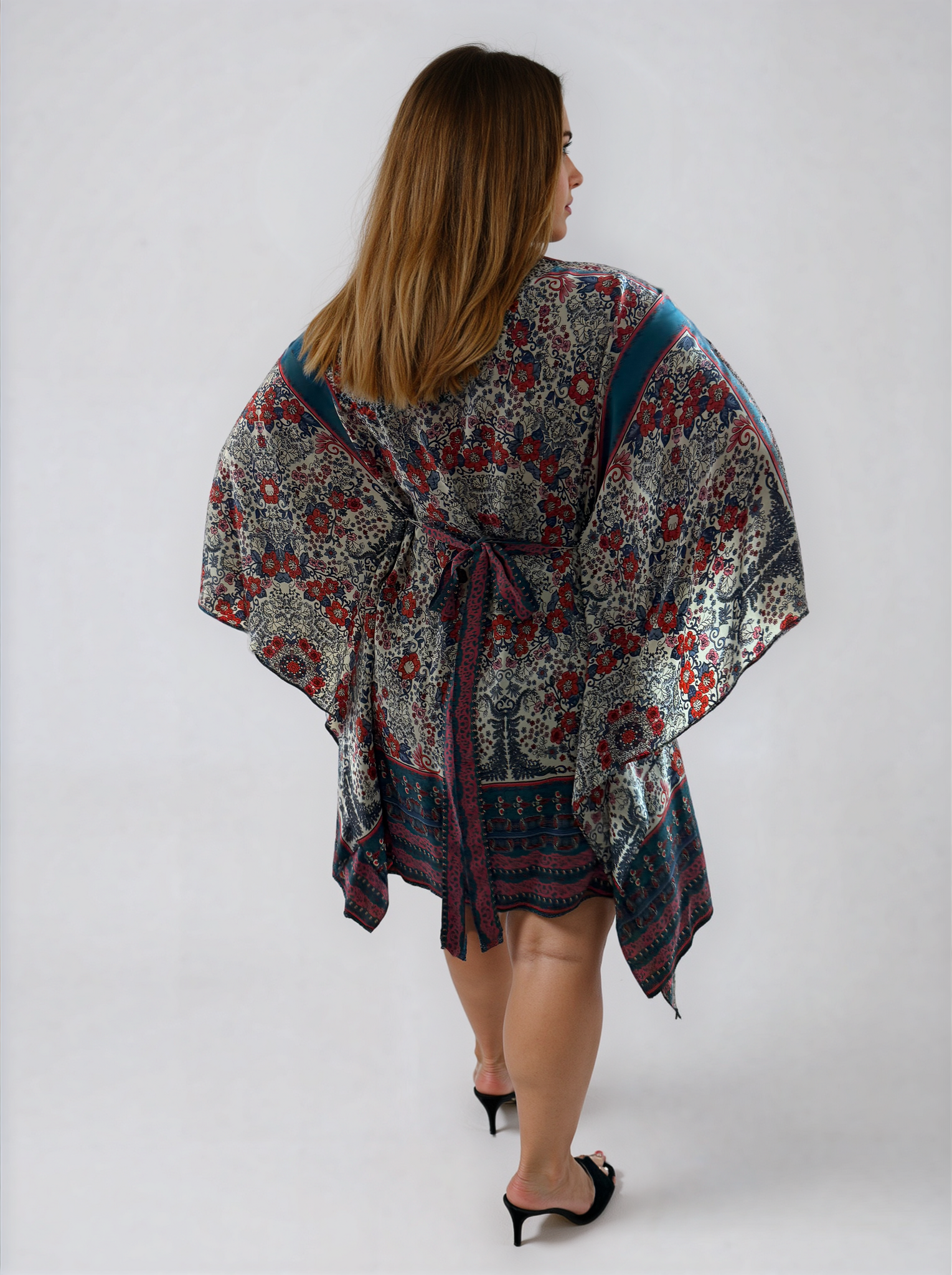 Back view of the ZALA rayon kaftan dress in Heirloom Blue, featuring a white ground adorned with intricate floral motifs, ornamental detailing, rich blue borders, and subtle berry accents inspired by heirloom textiles. The removable sash is tied at the back to softly define the waist, while flowing draped sleeves create an asymmetrical hem allowing for graceful movement from every angle.
