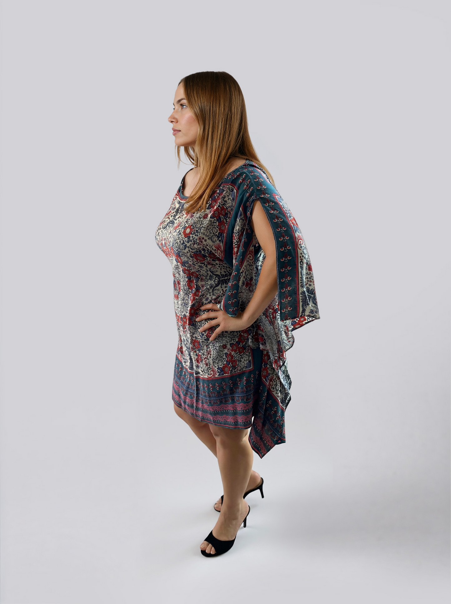 Side view of the ZALA rayon kaftan dress in Heirloom Blue, featuring a white ground adorned with intricate floral motifs, ornamental detailing, rich blue borders, and subtle berry accents inspired by heirloom textiles. The removable sash is tied at the back to softly define the waist, highlighting the fluid silhouette and draped sleeve slits.